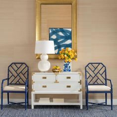 a living room with two chairs and a table in front of a painting on the wall