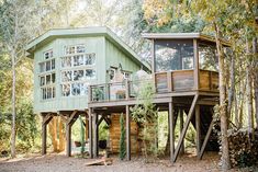 a green house in the woods surrounded by trees