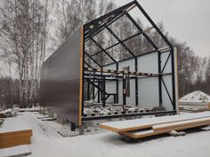 a metal structure sitting in the middle of snow covered ground next to wooden benches and trees