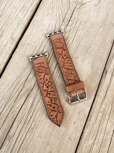 two leather watches straps sitting on top of a wooden table