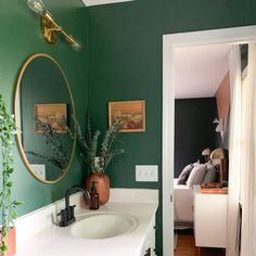 there is a bathroom with green walls and white cabinets in the room that has a mirror on the wall