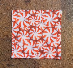 an orange and white quilted square on a brown surface with circles in the center