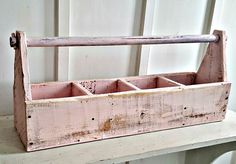 an old wooden box with compartments on top of a white table next to a wall