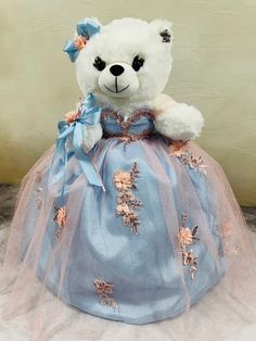 a white teddy bear wearing a blue dress