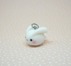 a small white plastic animal with a ring on it's head, sitting on a polka dot surface