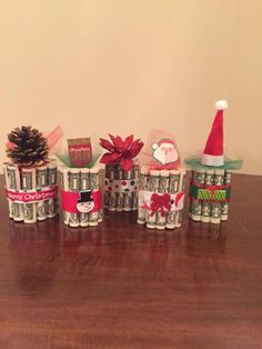 several stacks of money wrapped in christmas wrapping on top of a wooden table next to a pine cone