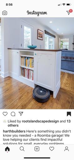 a roomba that is on the floor in front of a kitchen island with bookshelves