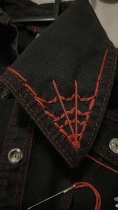 a pair of scissors are laying on the back of a black jean jacket with red stitching