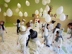 a group of children playing in a room with white balloons and snowman decorations on the ceiling