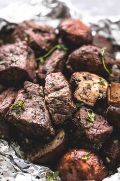 cooked steak and potatoes in foil with herbs on the top, ready to be eaten