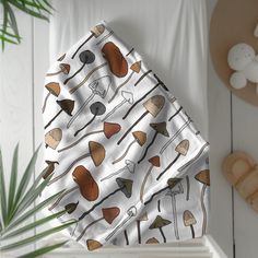 a blanket with mushrooms on it next to a potted plant and wooden spoons