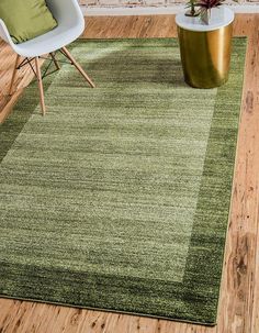 a green area rug in a living room next to a white chair and potted plant