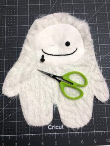 a pair of scissors sitting on top of a white stuffed animal with eyes and nose