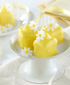 some yellow and white desserts with daisies on them are sitting on a plate