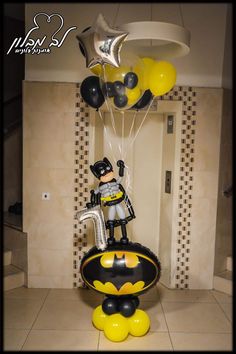 a batman balloon sculpture in the shape of a man on top of a batmobile