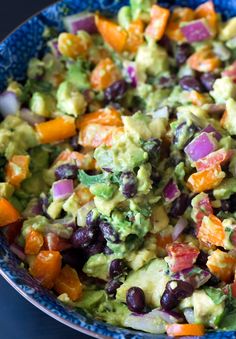 a bowl full of guacamole with black beans, carrots and onions