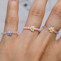 a woman's hand with three rings on it and two daisies in the middle