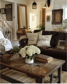 a living room filled with furniture and flowers on top of a wooden table in front of a staircase