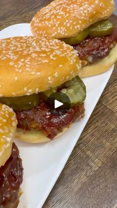 three hamburgers with pickles and cheese on a white plate