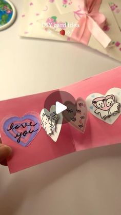 someone is holding up some heart shaped magnets on a piece of pink paper that says i love you