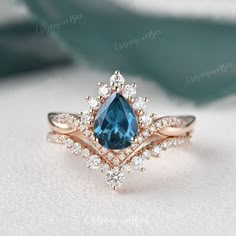 an engagement ring with a pear shaped blue stone surrounded by small white and rose cut diamonds