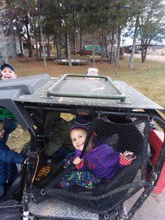 three children sitting in the back of a vehicle