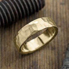 a gold wedding ring sitting on top of a wooden table next to a knife and other items