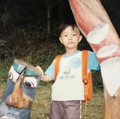 a young boy standing next to a wooden statue