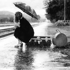 a painting of a woman with an umbrella kneeling on a train track in the rain