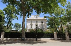 a large white building with a clock on it's face and trees in the foreground