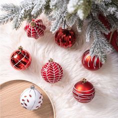 red and white christmas ornaments sitting on top of a fur covered floor next to a tree