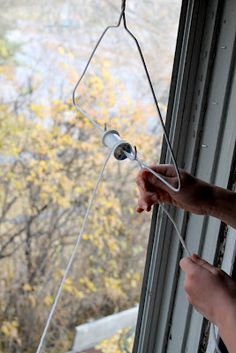 a person is holding something in their hand while looking out the window at some trees