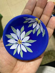 a hand holding a blue plate with white flowers painted on it