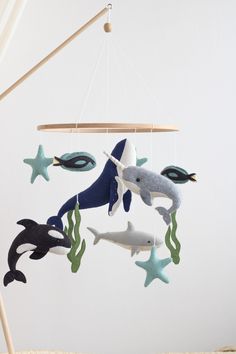 a mobile with two dolphins and three stars hanging from it's sides in front of a white wall