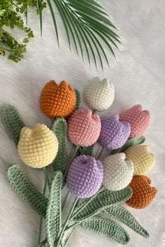 crocheted flowers are arranged on a white furnishing area with palm leaves