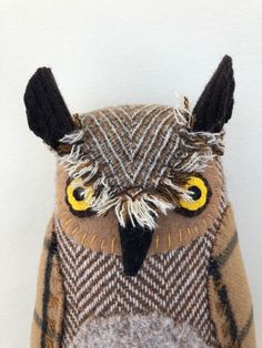 an owl stuffed animal with yellow eyes and black ears, sitting on a white surface