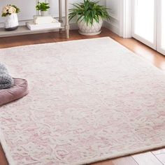 a white rug on the floor in a living room with wooden floors and potted plants