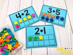 three blue boxes filled with different colored shapes and numbers on top of a white table