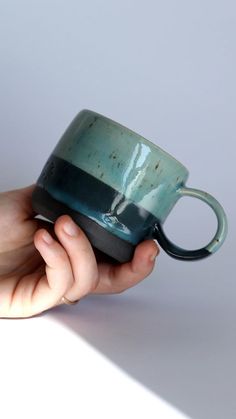 a hand holding a blue and black coffee cup