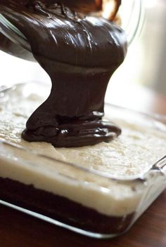 someone is adding chocolate to the batter in a glass dish on top of a wooden table