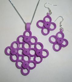 a purple necklace and earring set on a white surface