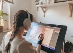 a woman sitting in front of a computer screen with headphones on and writing on the screen