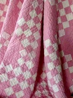 a pink and white checkered quilt on a bed