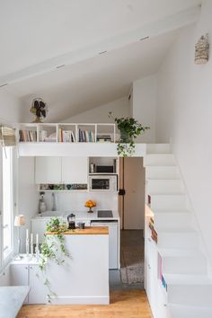 an open kitchen and living room with stairs leading up to the loft