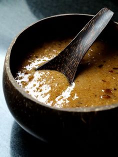 a wooden spoon sitting in a bowl filled with brown liquid on top of a table