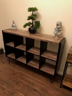 a wooden shelf sitting next to a small tree on top of a hard wood floor