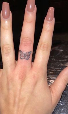 a woman's hand with a butterfly tattoo on the middle finger, and a ring