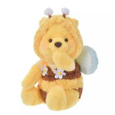 a yellow teddy bear with flowers on it's chest and wings in its mouth