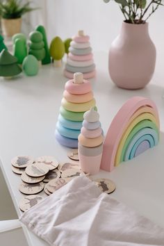 there are many different colored wooden toys on the table with flowers in vases behind them