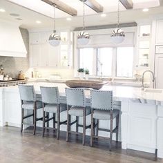 a large kitchen with lots of counter space and chairs around the center island in front of an oven